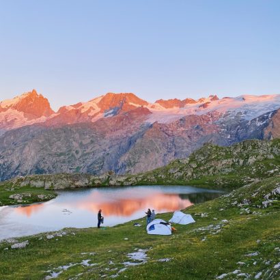 a couple of people standing on top of a lush green hillside